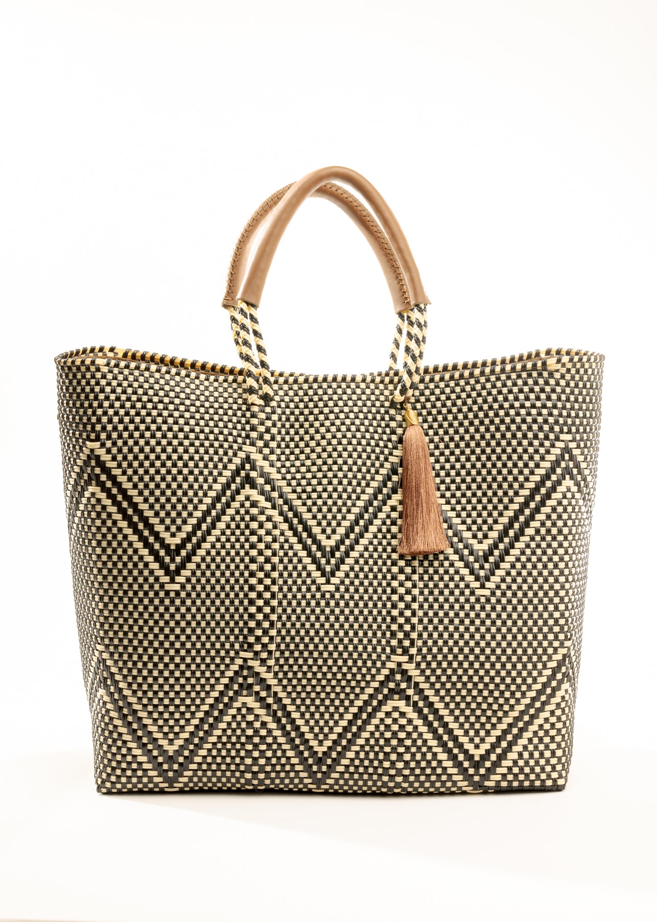 Tan, cream, and brown chevron tote bag made from recycled plastics featuring a tan leather handle and tassel detail