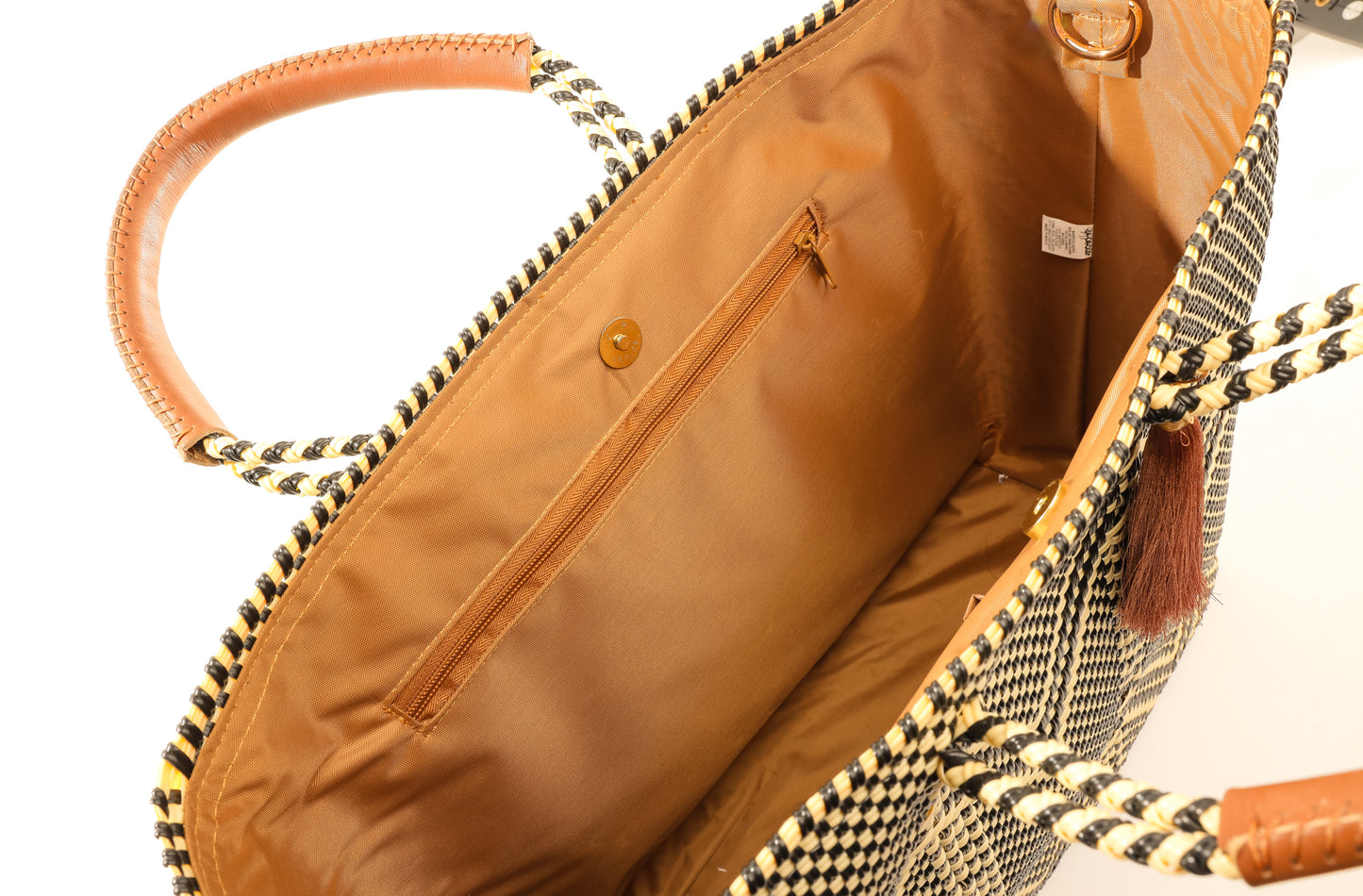 Inside tan lining featuring a zipper pocket and magnetic closure of tan, cream, and brown chevron tote bag made from recycled plastics