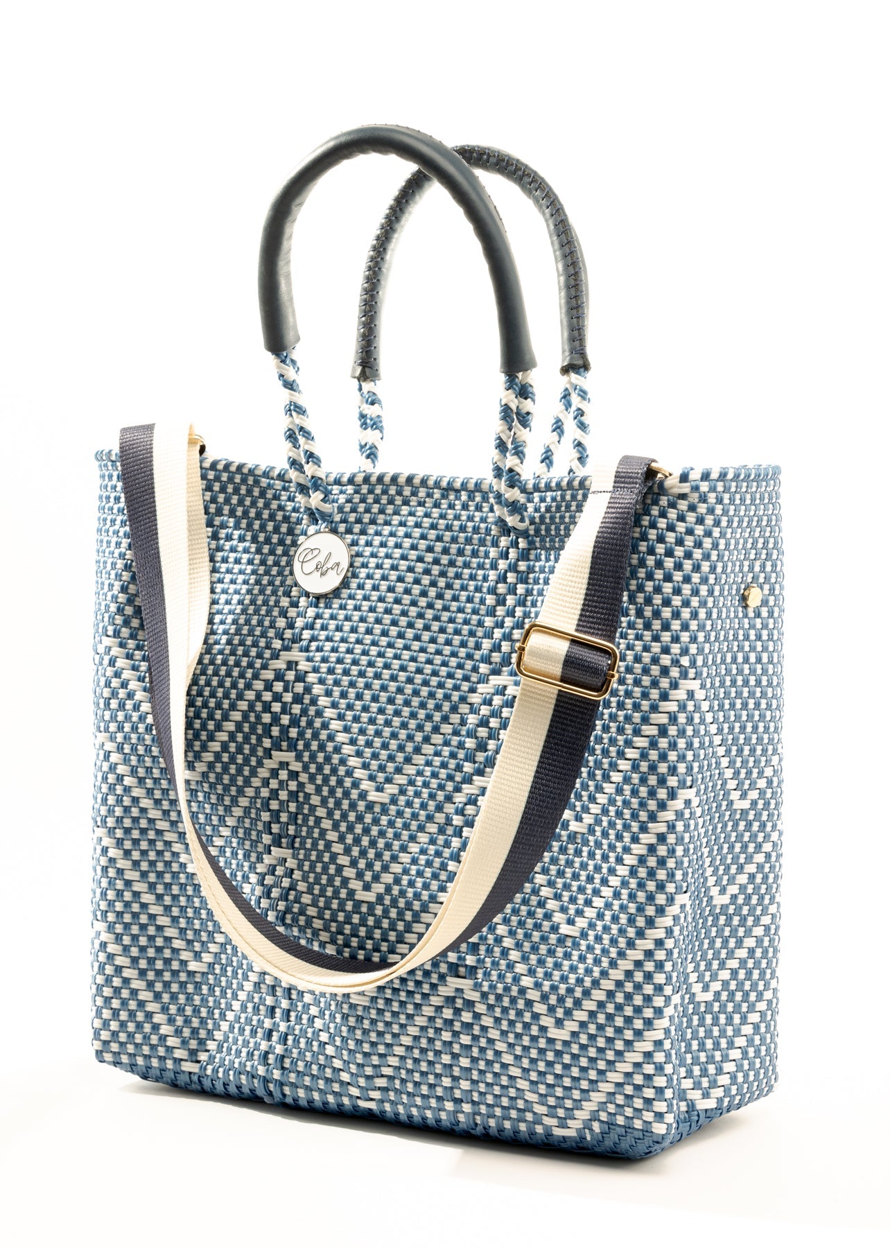 Blue and white chevron woven bucket bag made from recycled plastics featuring navy blue leather handles and a silver Coba medallion with option woven strap added