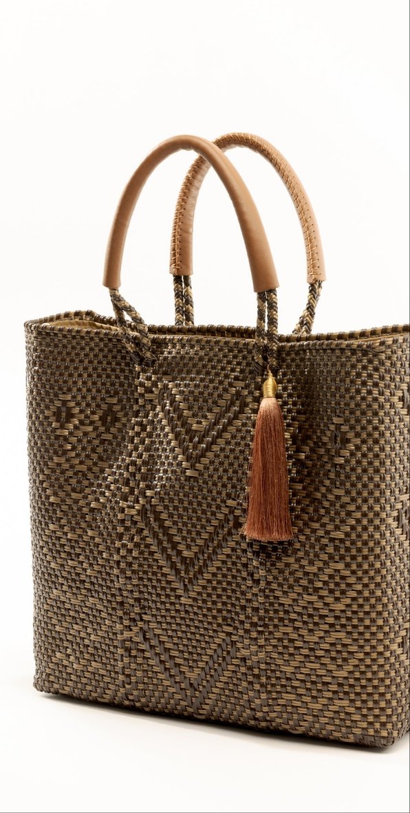 Side angle of brown and tan chevron woven bucket bag made from recycled plastics and featuring a tan leather handle and tassel detail