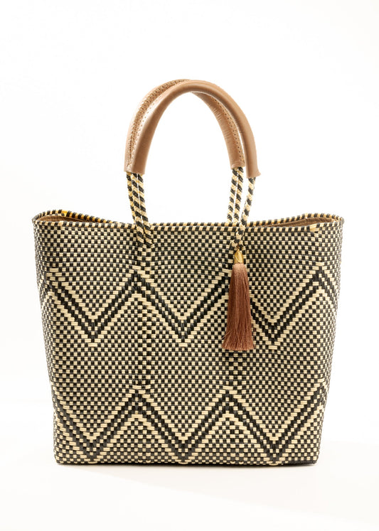 Brown, cream, and tan chevron pattern woven bucket tote made from recycled plastics and featuring tan leather handles and tassel detail