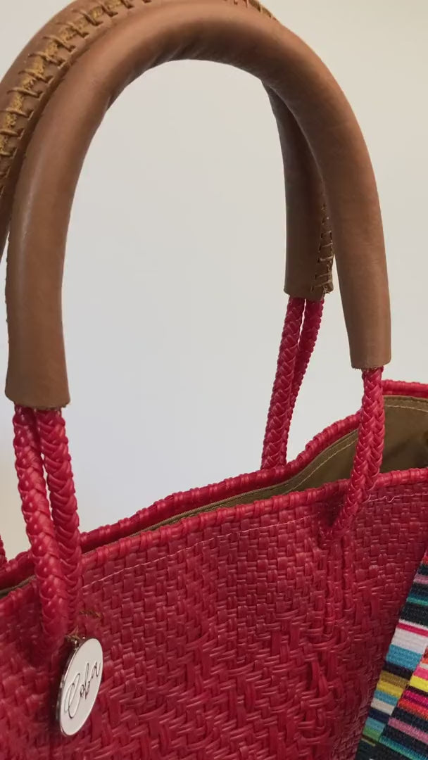 Video of red woven bag with rainbow striped strap