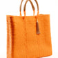 Side angle of orange woven tote bag made from recycled plastics with tan handles and tan tassel detail