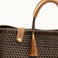 Closeup of brown woven material, leather straps, and tassel on handbag