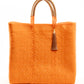 Orange woven tote bag made from recycled plastics with tan handles and tan tassel detail