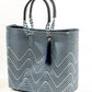 Side angle of navy blue and white chevron tote bag made from recycled plastics featuring a blue handle and navy tassel detail