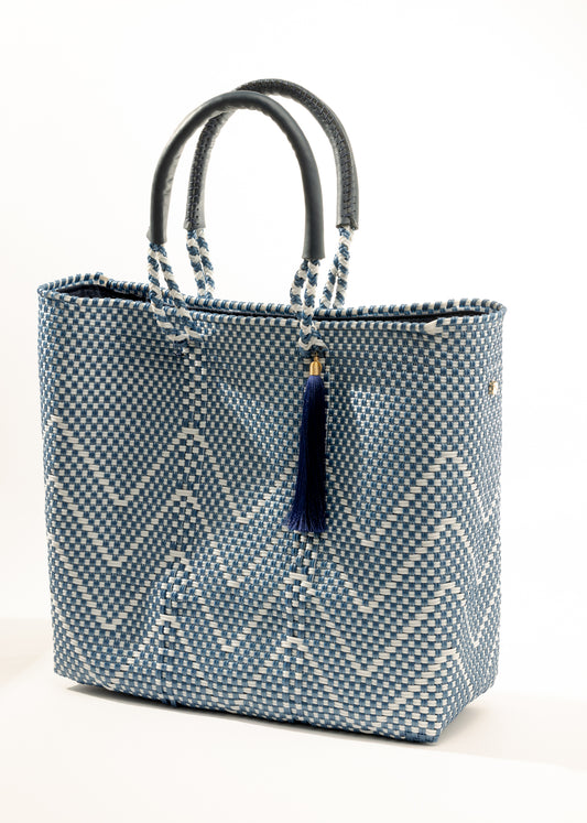 Side angle of navy blue and white chevron tote bag made from recycled plastics featuring a blue handle and navy tassel detail