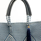 Closeup of woven texture of navy blue and white chevron handbag with leather handles and blue tassel