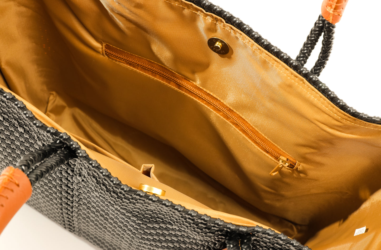 Inside tan lining with zipper pocket and magnetic closure of Black and brown woven bucket bag made from recycled plastics 