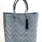 Blue and white chevron woven bucket bag made from recycled plastics featuring navy blue leather handles and tassel detail