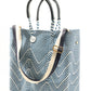 Blue and white chevron woven bucket bag made from recycled plastics featuring navy blue leather handles and a silver Coba medallion with option woven strap added