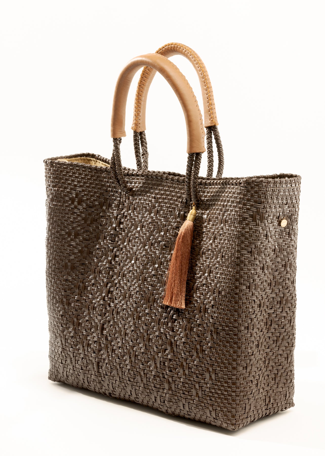 Side angle of brown and tan woven handbag made from recycled plastics featuring tan leather handles and tassel detail