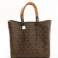 Brown and tan woven handbag made from recycled plastics featuring tan leather handles and silver Coba medallion