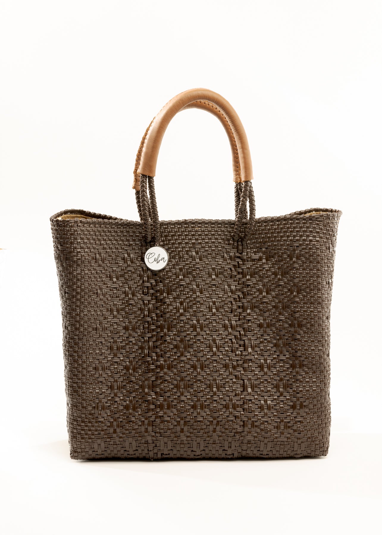 Brown and tan woven handbag made from recycled plastics featuring tan leather handles and silver Coba medallion