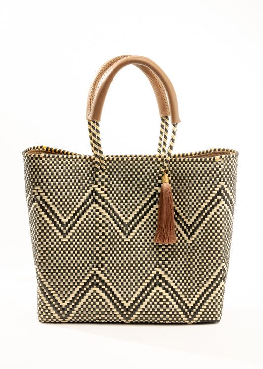 Brown, cream, and tan chevron pattern woven bucket tote made from recycled plastics and featuring tan leather handles and tassel detail