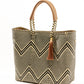 Angles view of brown, cream, and tan chevron pattern woven bucket tote made from recycled plastics and featuring tan leather handles and tassel detail