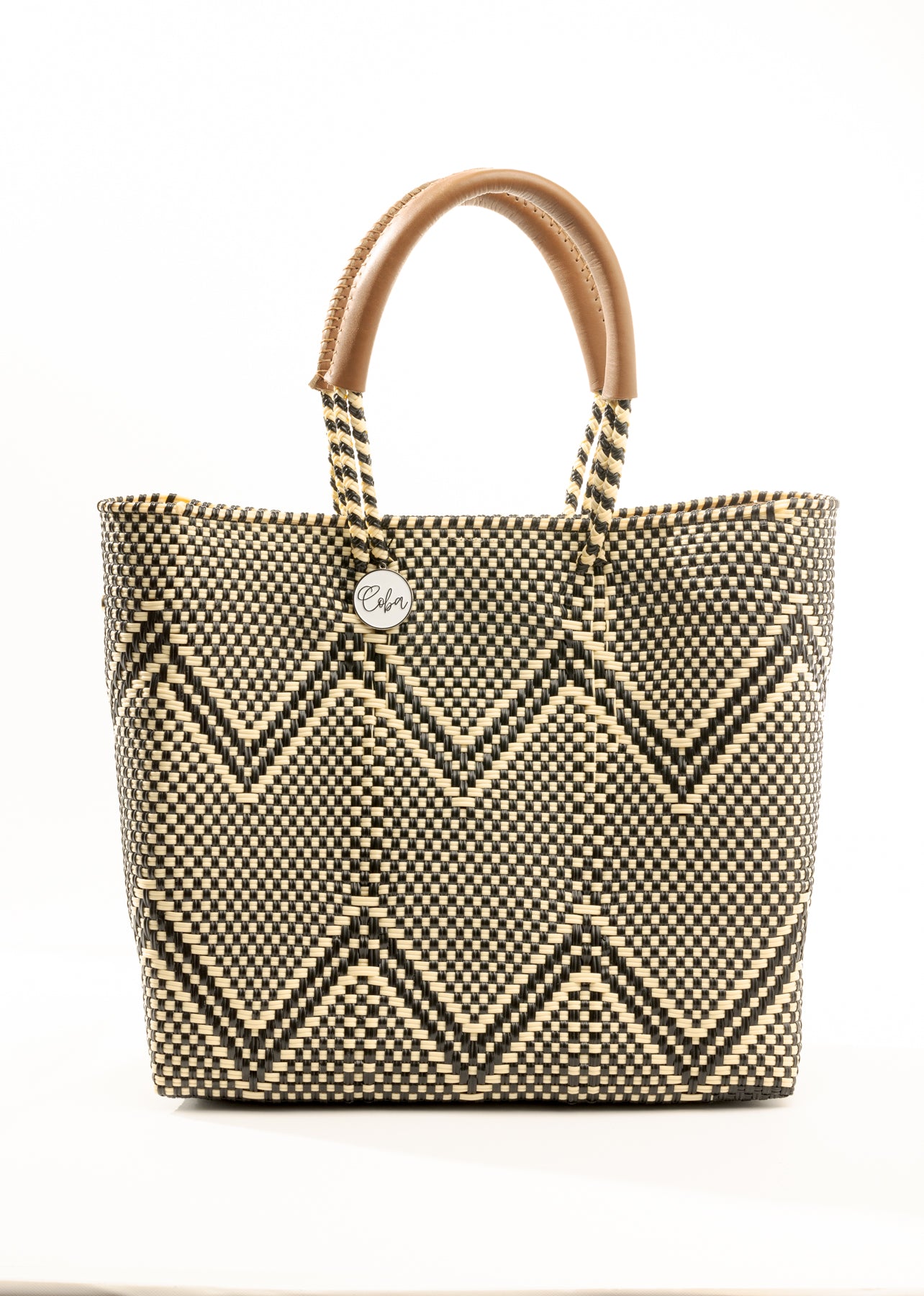 Brown, cream, and tan chevron pattern woven bucket tote made from recycled plastics and featuring tan leather handles and silver Coba logo medallion