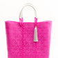 Hot pink woven bucket bag made from recycled plastics featuring a white leather handle and white tassel detail