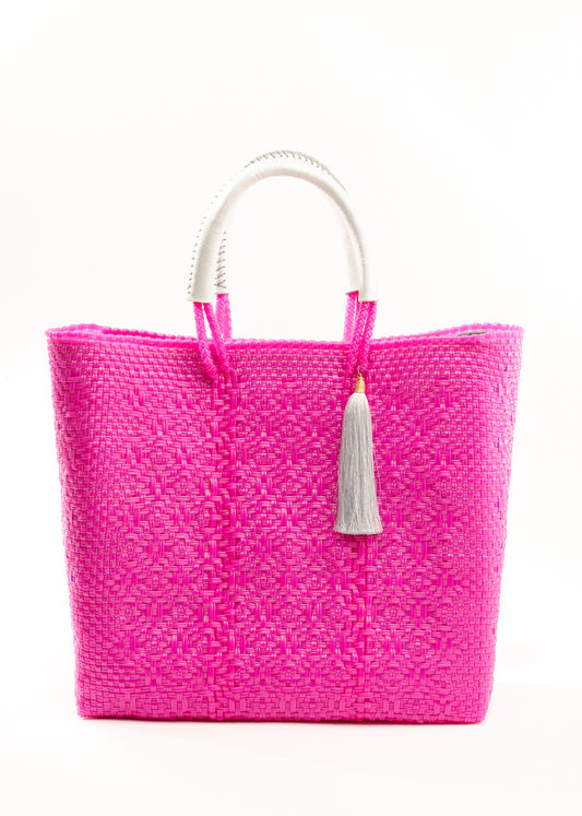 Hot pink woven bucket bag made from recycled plastics featuring a white leather handle and white tassel detail