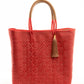 Red woven bucket bag made from recycled plastics with tan leather handle and tassel