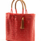 Angled view of red woven bucket bag made from recycled plastics with tan leather handle and tassel