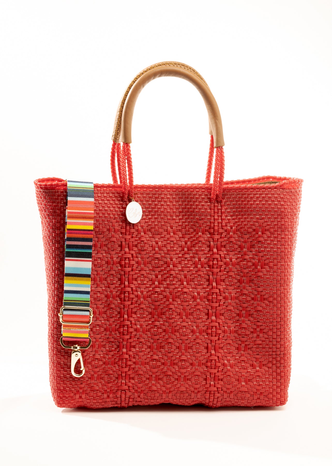 Rainbow striped purse strap hanging over red woven tote bag